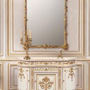 Комод и роскошное зеркало в золотой раме.