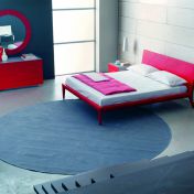 Красная кровать на деревянных ножках.